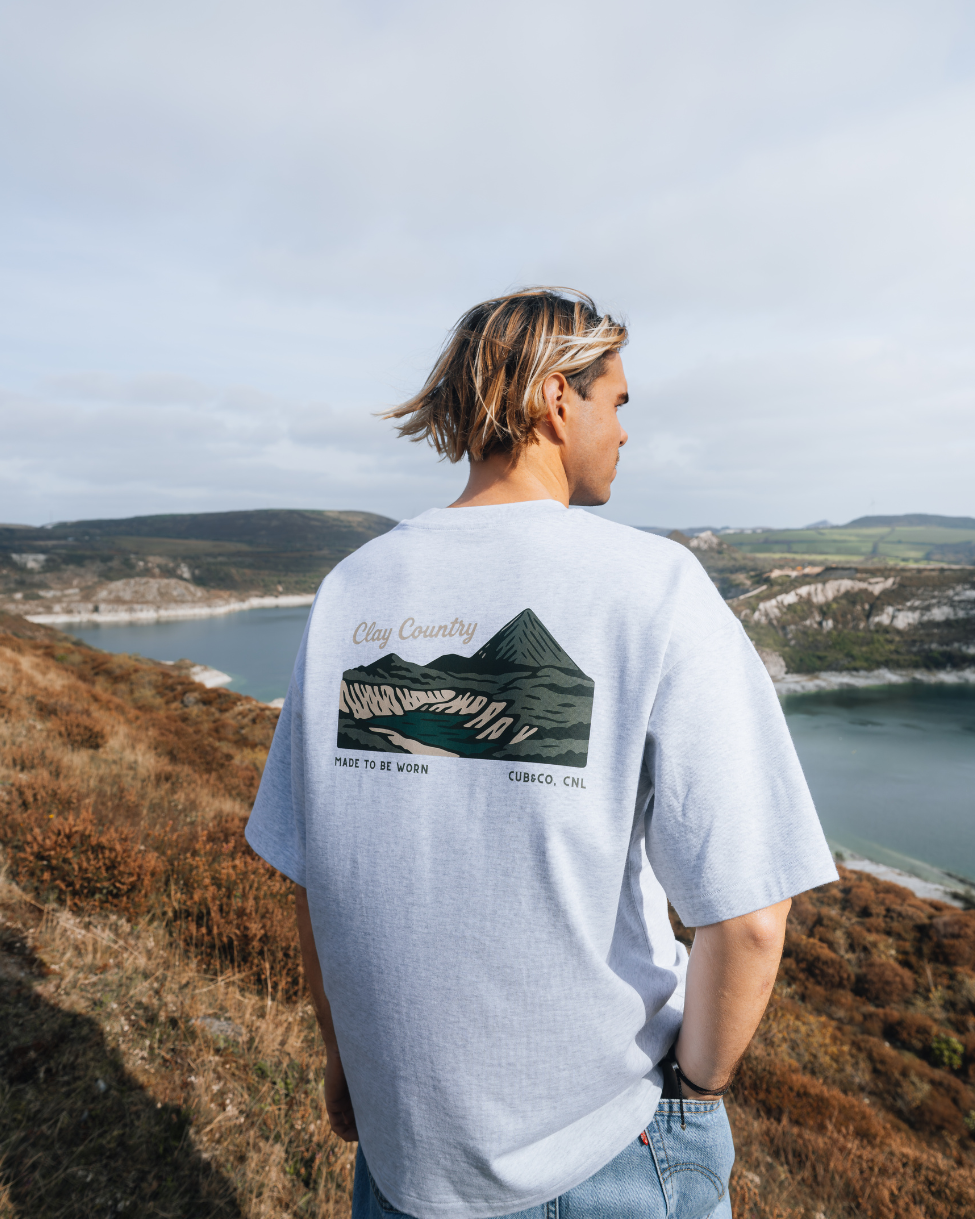 Person wearing a t-shirt with a mountain graphic in a scenic outdoor setting