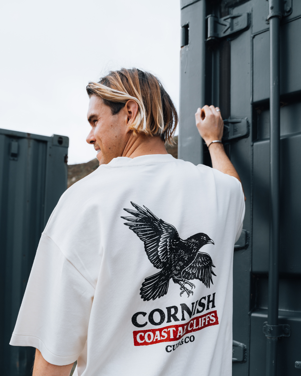 Person wearing a white t-shirt with a bird graphic and &