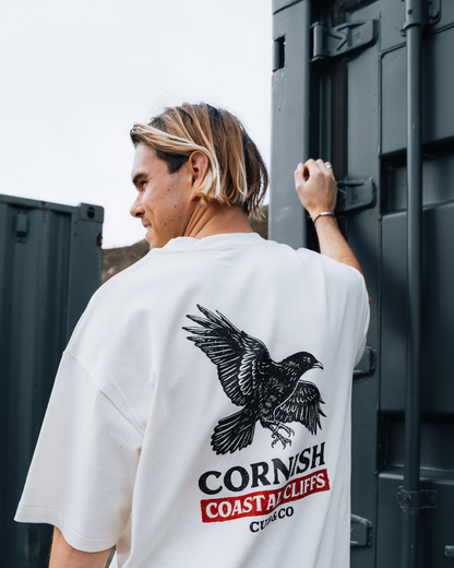 Person wearing a white t-shirt with a bird graphic and &